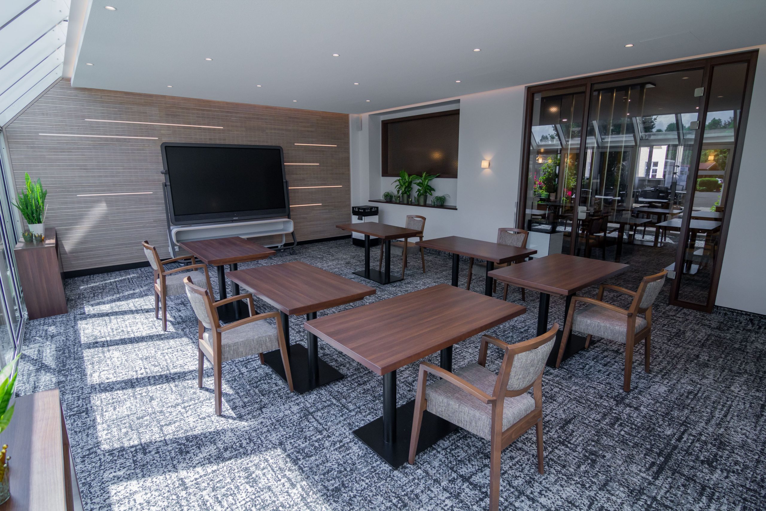 Tagungsraum 3 mit Tischen, Stühlen und Multitouch-Display und Blick in die Lobby - skaliert