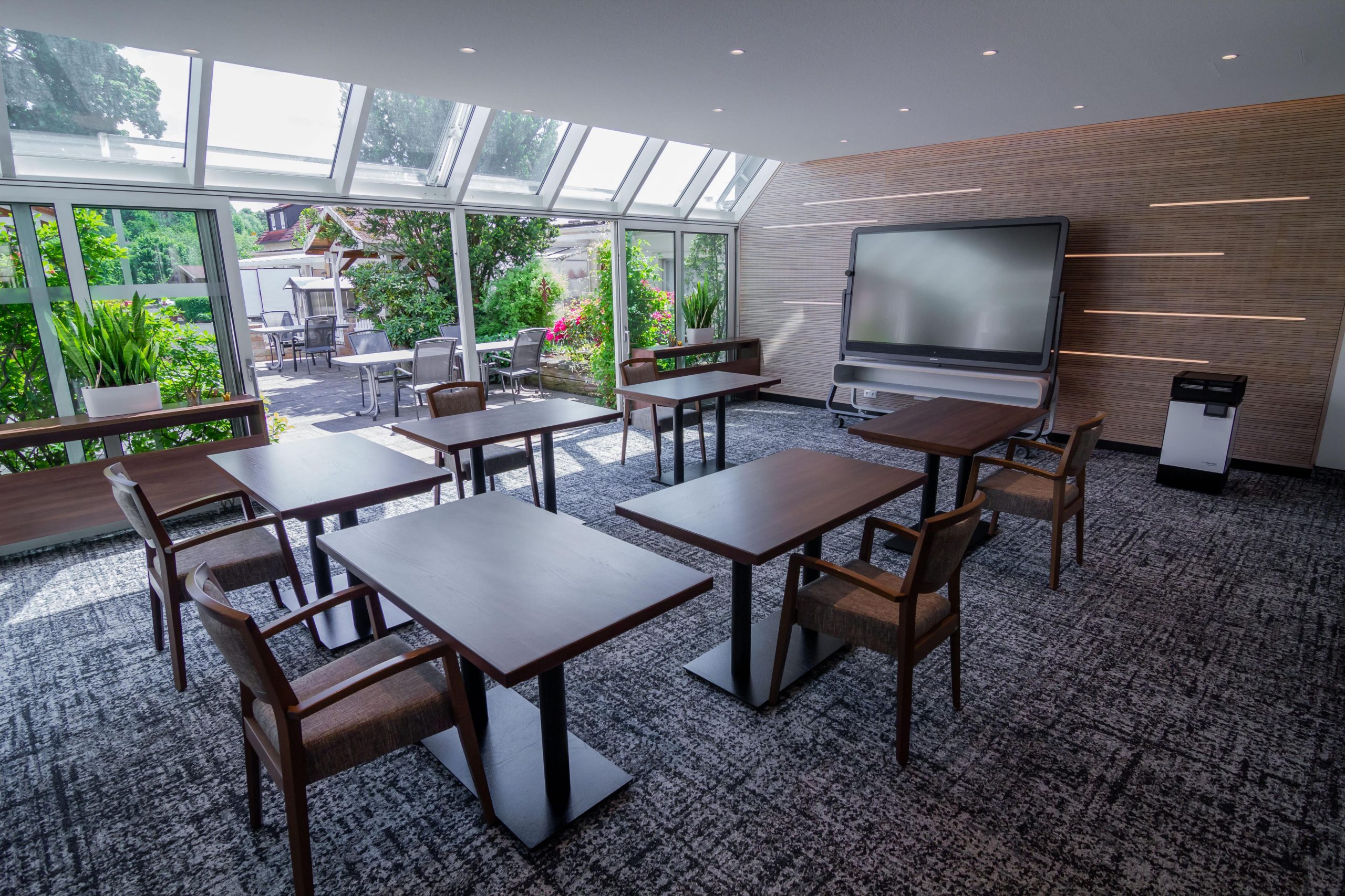 Tagungsraum 3 mit Tischen, Stühlen und Multitouch-Display und Blick auf Terrasse